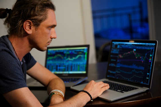 day trader looking at laptop studying candlestick charts